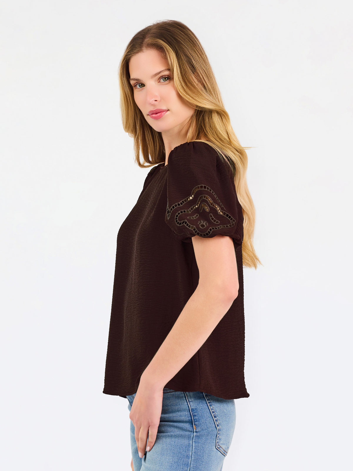 Blonde woman wearing a short sleeve brown colored top with cut out detail on puff sleeves