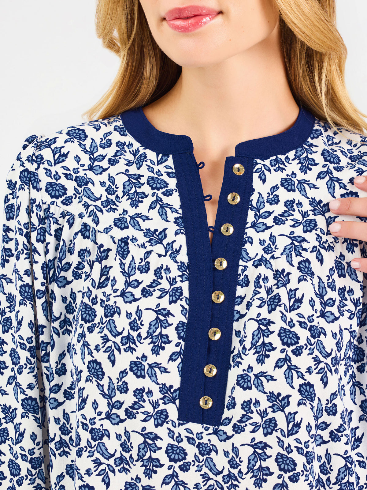 Blonde woman wearing a long sleeve blue floral navy top with blue neckline 