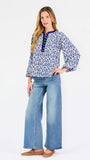 Blonde woman wearing a long sleeve blue floral navy top with blue neckline 