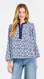 Blonde woman wearing a long sleeve blue floral navy top with blue neckline 