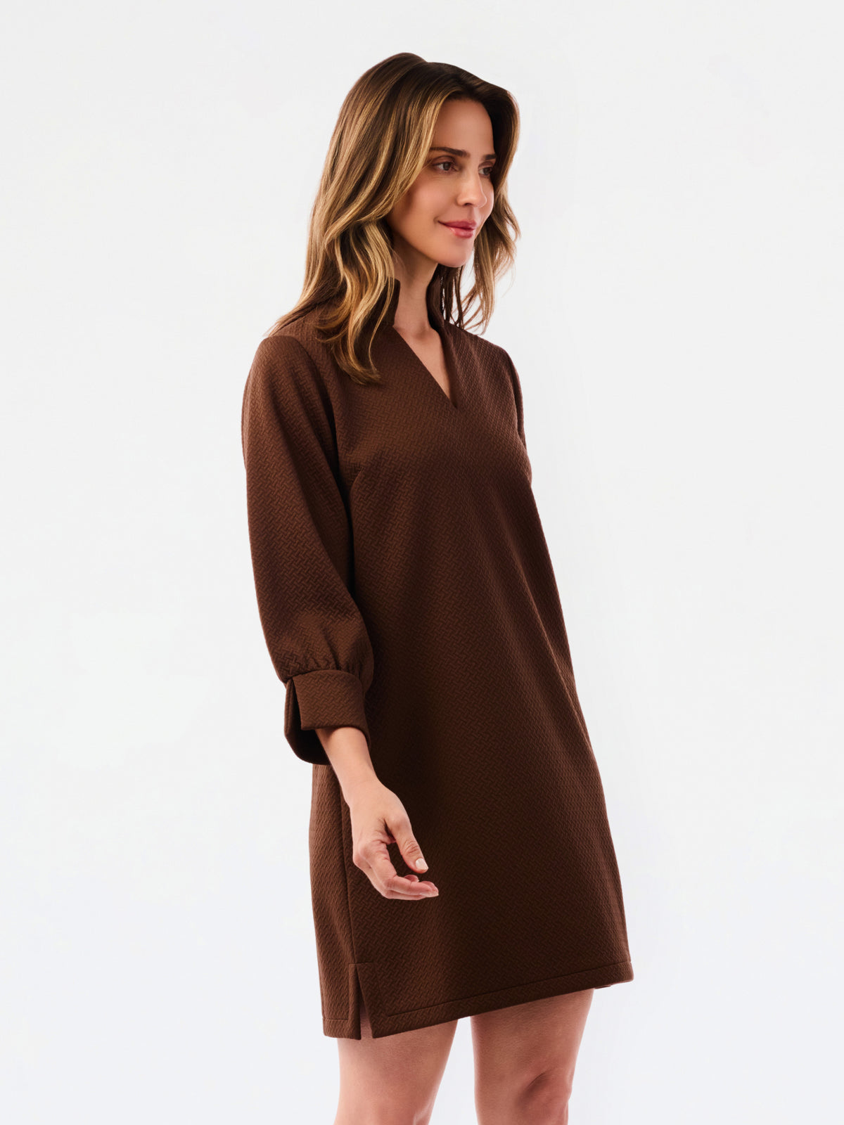 Woman wearing a textured three quarter sleeve brown dress on a white background