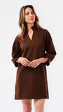 Woman wearing a textured three quarter sleeve brown dress on a white background