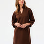 Woman wearing a textured three quarter sleeve brown dress on a white background