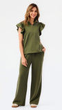 A woman modeling a matching olive green two-piece set consisting of a ruffled short-sleeve quarter-zip top and wide-leg pants, photographed against a clean white studio background.