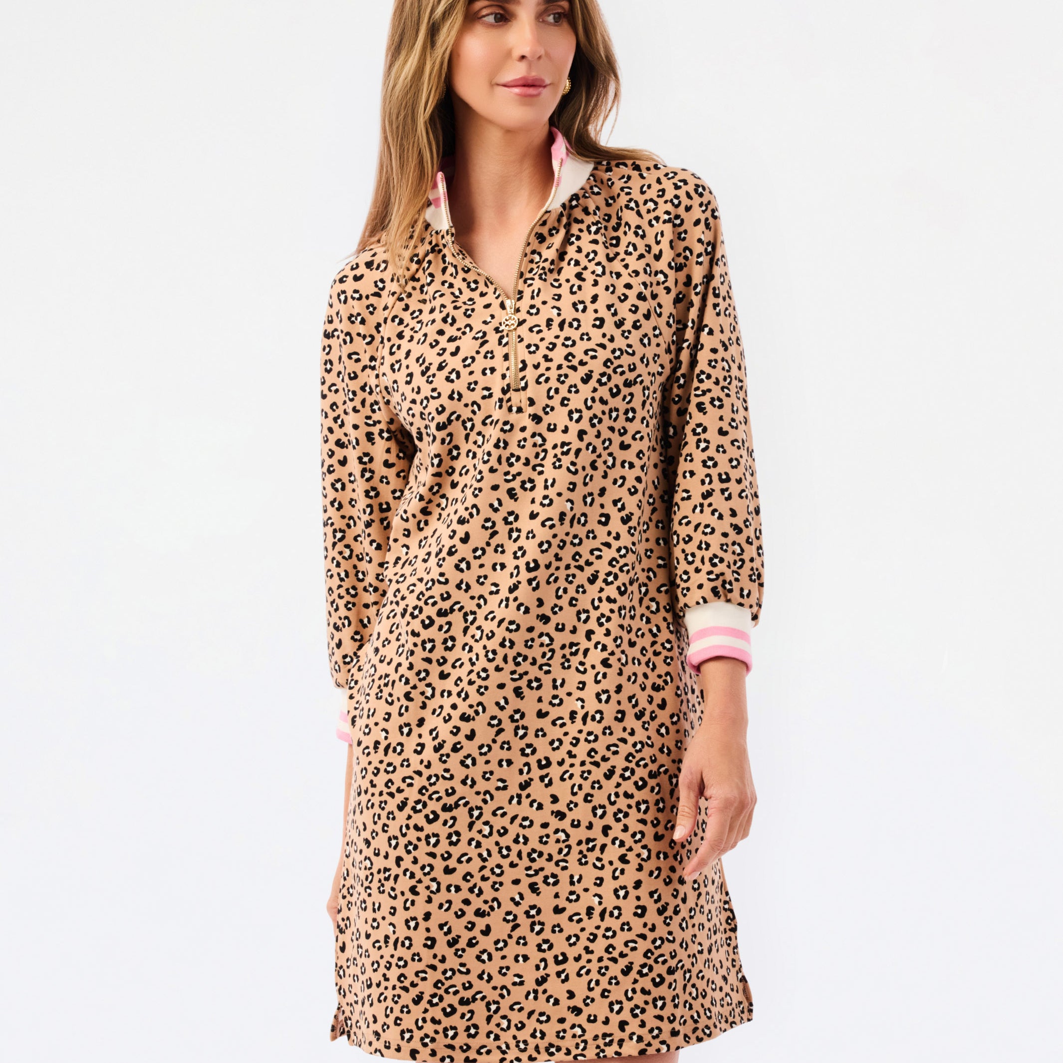 A woman modeling a leopard print long-sleeve shirt dress with a pink inner collar and cuffs, set against a plain white studio background.