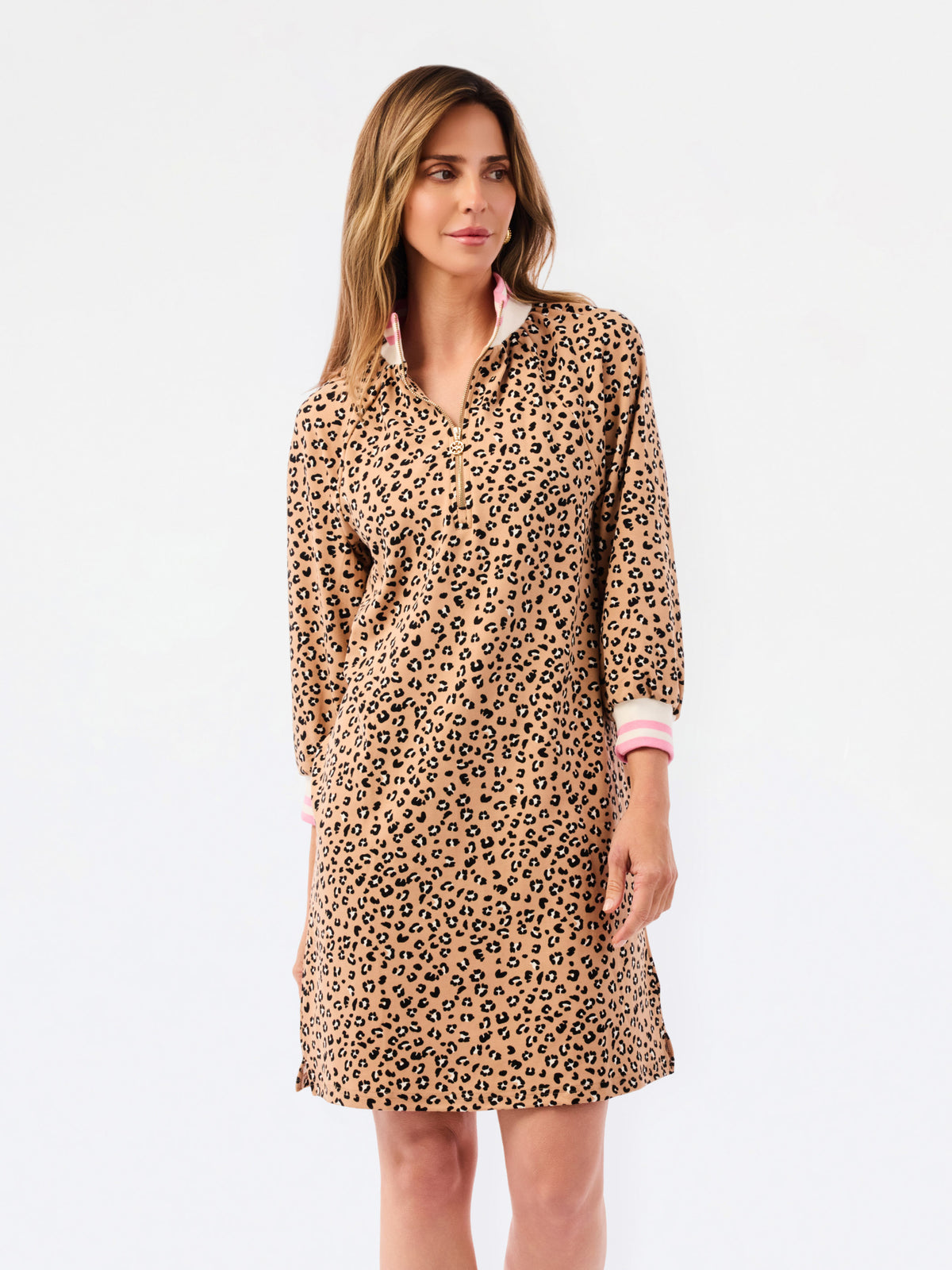 A woman modeling a leopard print long-sleeve shirt dress with a pink inner collar and cuffs, set against a plain white studio background.