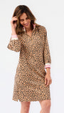 A woman modeling a long-sleeve leopard-print dress with pink and white striped cuffs, set against a plain white studio background.