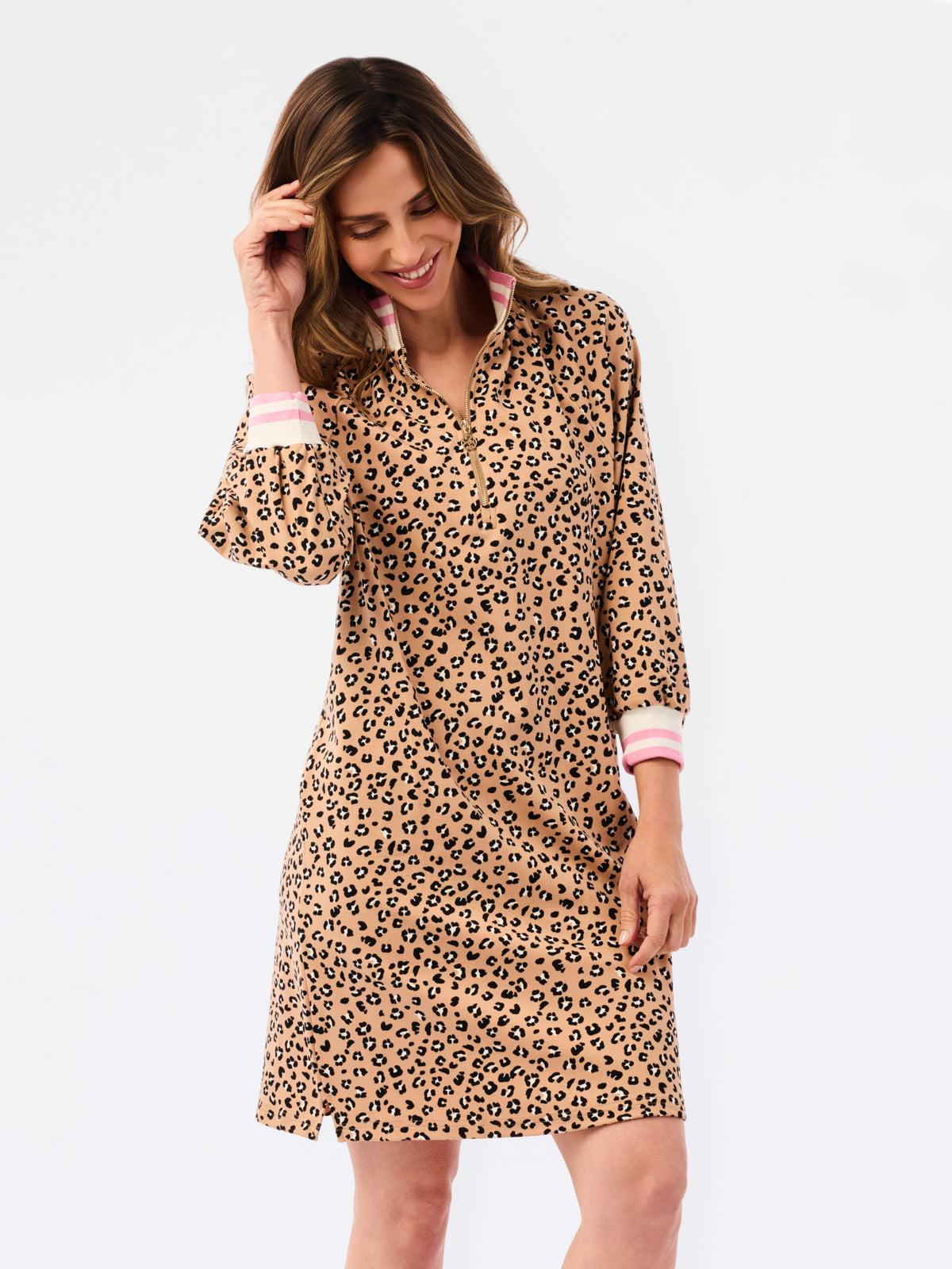 A woman modeling a long-sleeve leopard-print dress with pink and white striped cuffs, set against a plain white studio background.