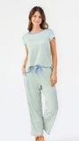 Woman wearing a green and white striped short sleeve pajama set with blue trim on a white background