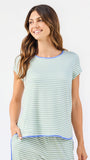 Woman wearing a green and white striped short sleeve pajama set with blue trim on a white background