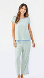 Woman wearing a green and white striped short sleeve pajama set with blue trim on a white background