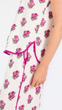 Brown haired woman wearing a  pink and green floral pajama set with pink trim on a white background