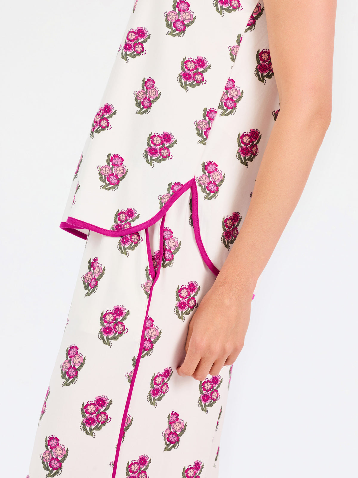 Brown haired woman wearing a  pink and green floral pajama set with pink trim on a white background