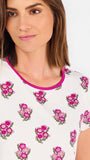 Brown haired woman wearing a  pink and green floral pajama set with pink trim on a white background