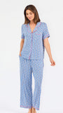 Woman wearing a blue striped pajama set with bees and stripes and a pink trim on a white background