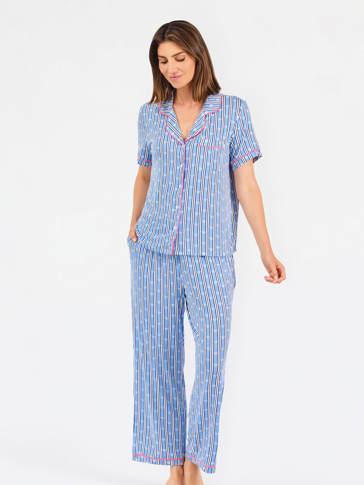 Woman wearing a blue striped pajama set with bees and stripes and a pink trim on a white background