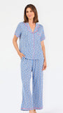 Woman wearing a blue striped pajama set with bees and stripes and a pink trim on a white background