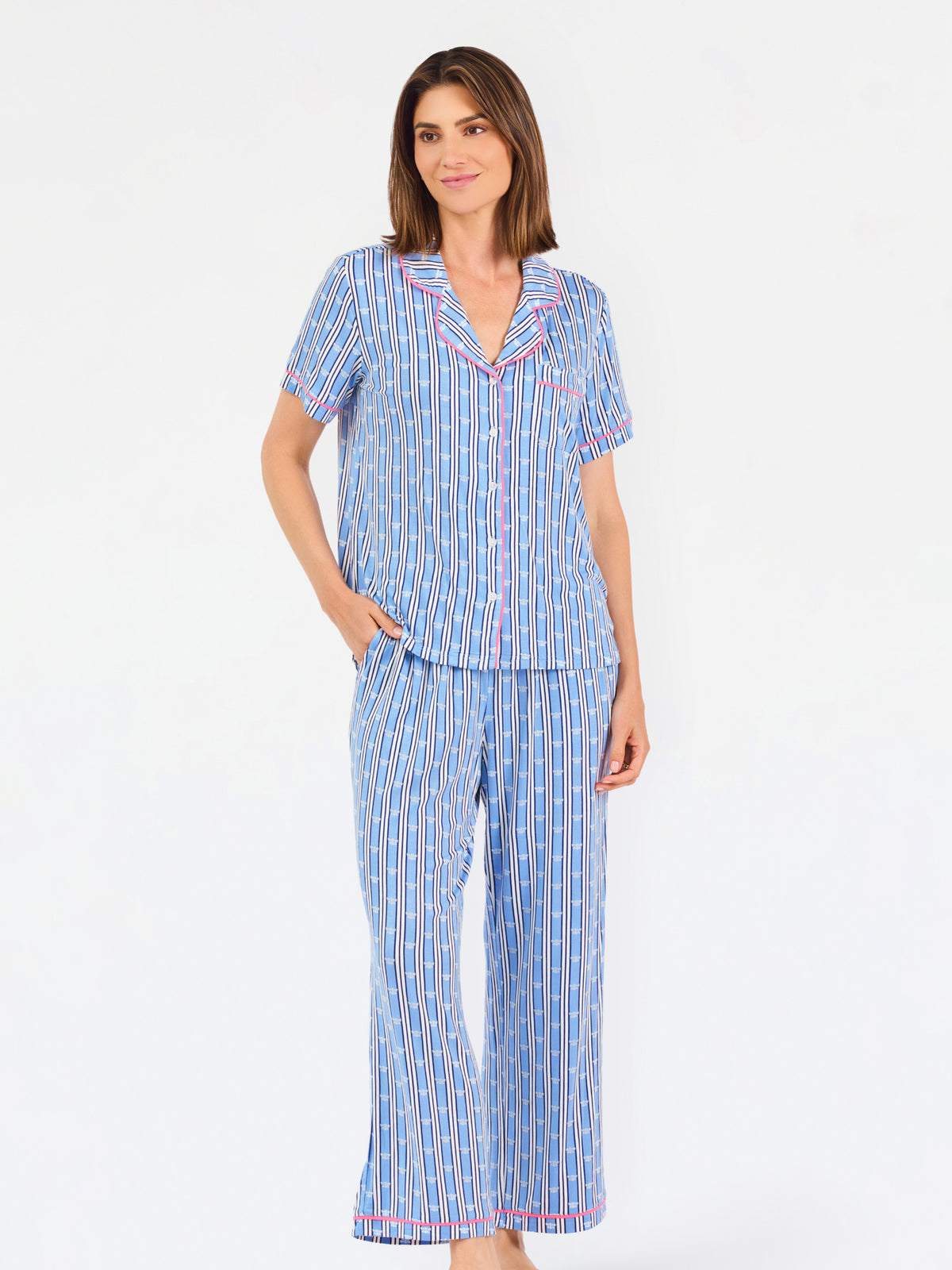 Woman wearing a blue striped pajama set with bees and stripes and a pink trim on a white background