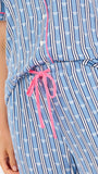 Woman wearing a blue striped pajama set with bees and stripes and a pink trim on a white background