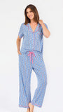 Woman wearing a blue striped pajama set with bees and stripes and a pink trim on a white background