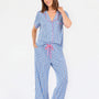 Woman wearing a blue striped pajama set with bees and stripes and a pink trim on a white background
