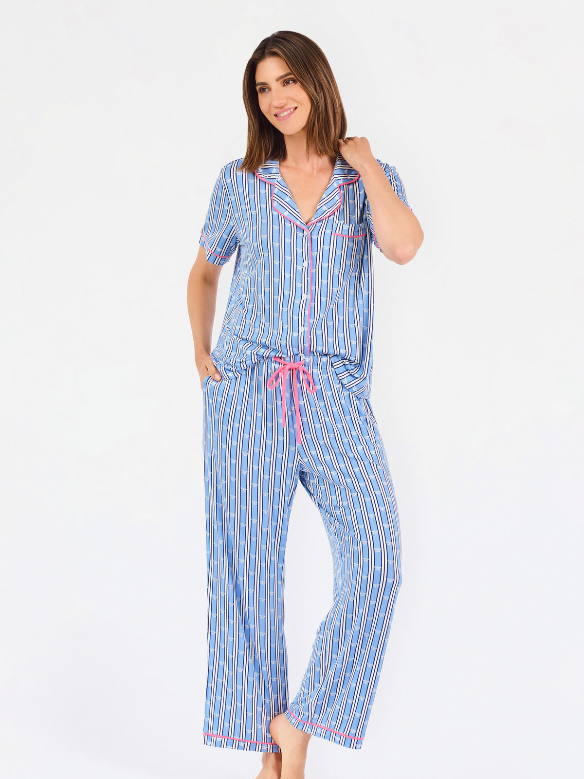 Woman wearing a blue striped pajama set with bees and stripes and a pink trim on a white background