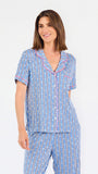Woman wearing a blue striped pajama set with bees and stripes and a pink trim on a white background