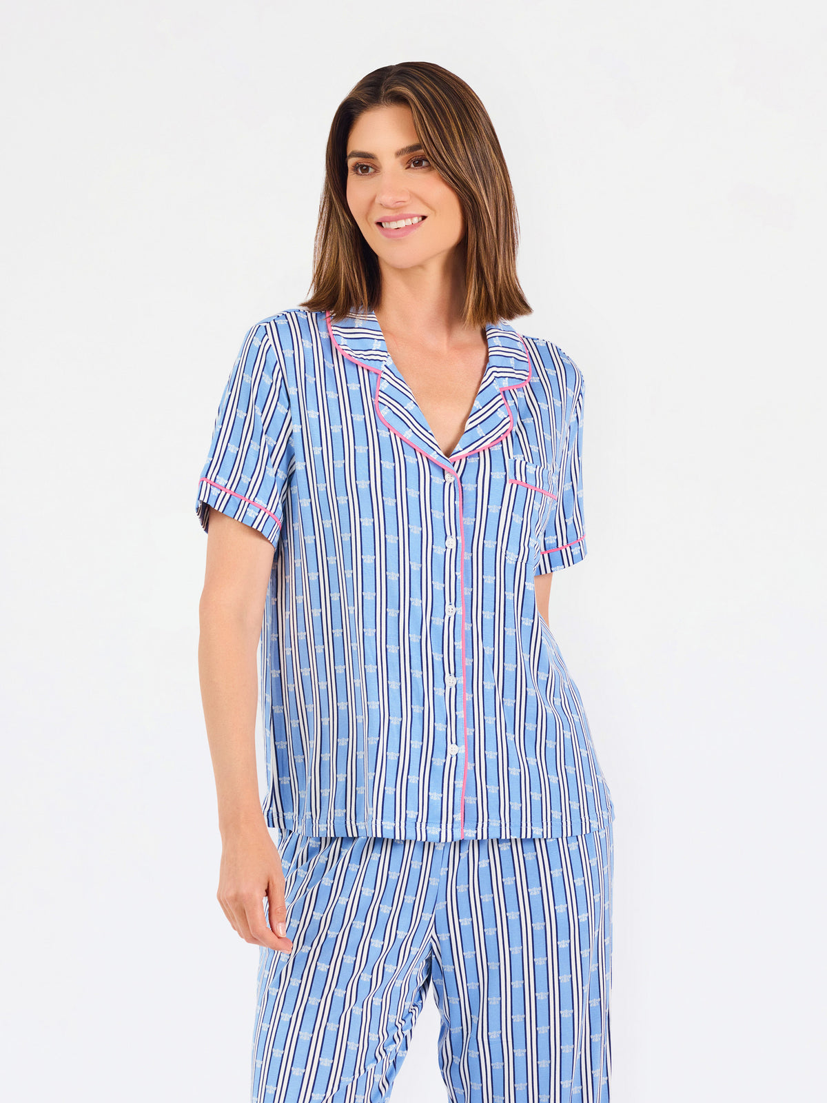 Woman wearing a blue striped pajama set with bees and stripes and a pink trim on a white background