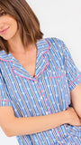 Woman wearing a blue striped pajama set with bees and stripes and a pink trim on a white background