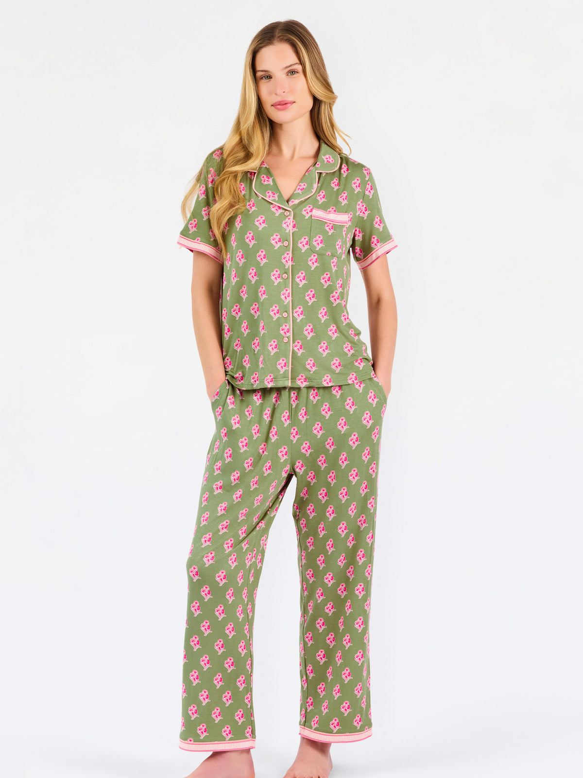 Woman wearing a green and pink floral pajama set on a white background