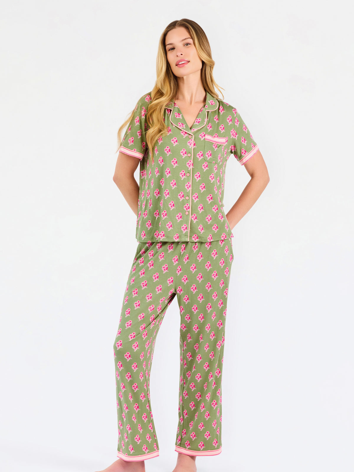 Woman wearing a green and pink floral pajama set on a white background