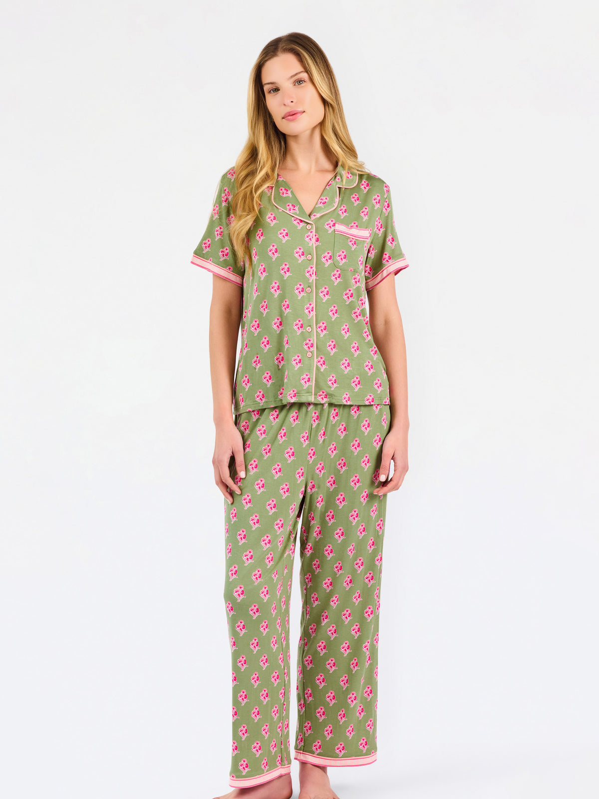 Woman wearing a green and pink floral pajama set on a white background