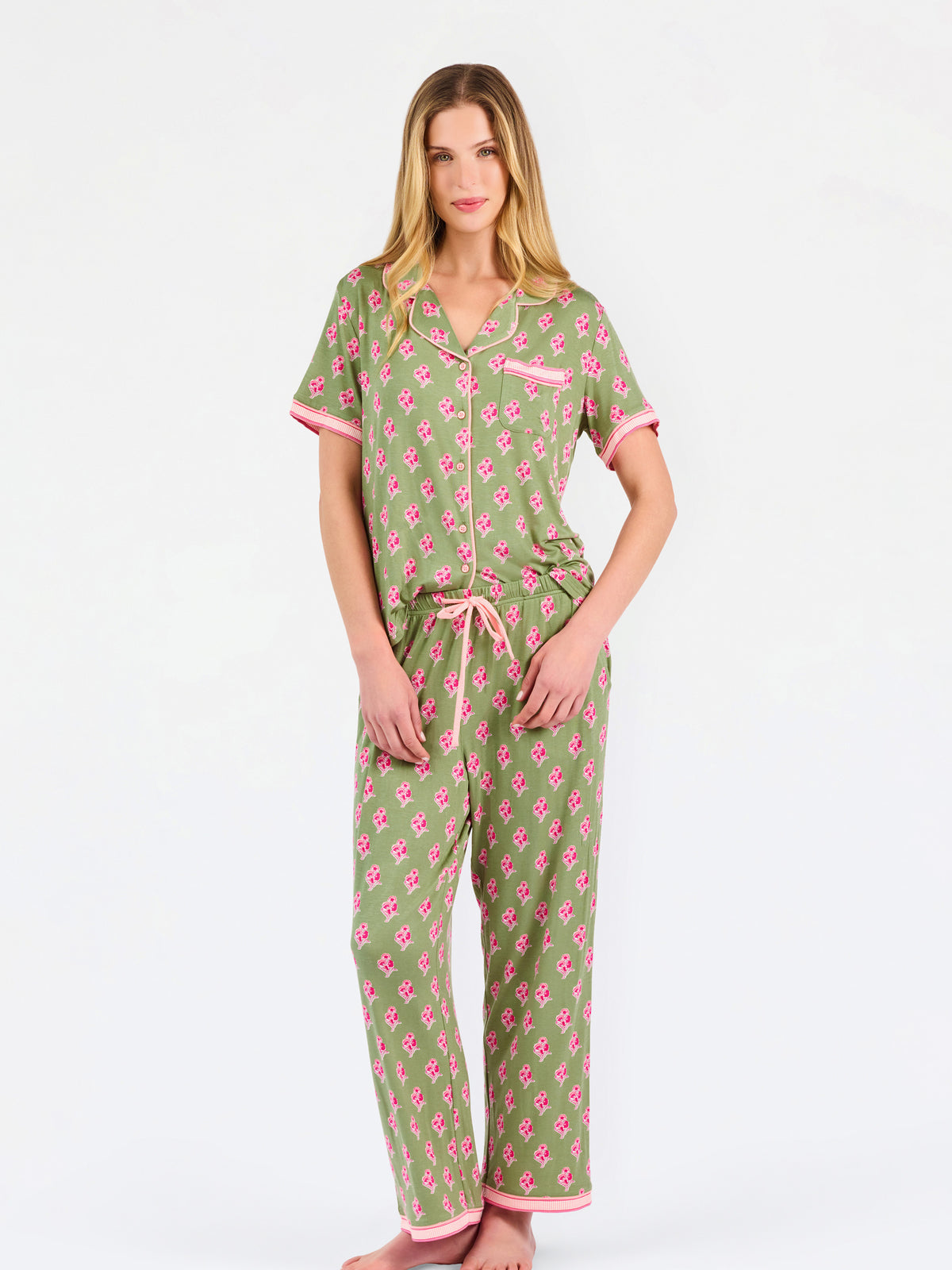 Woman wearing a green and pink floral pajama set on a white background