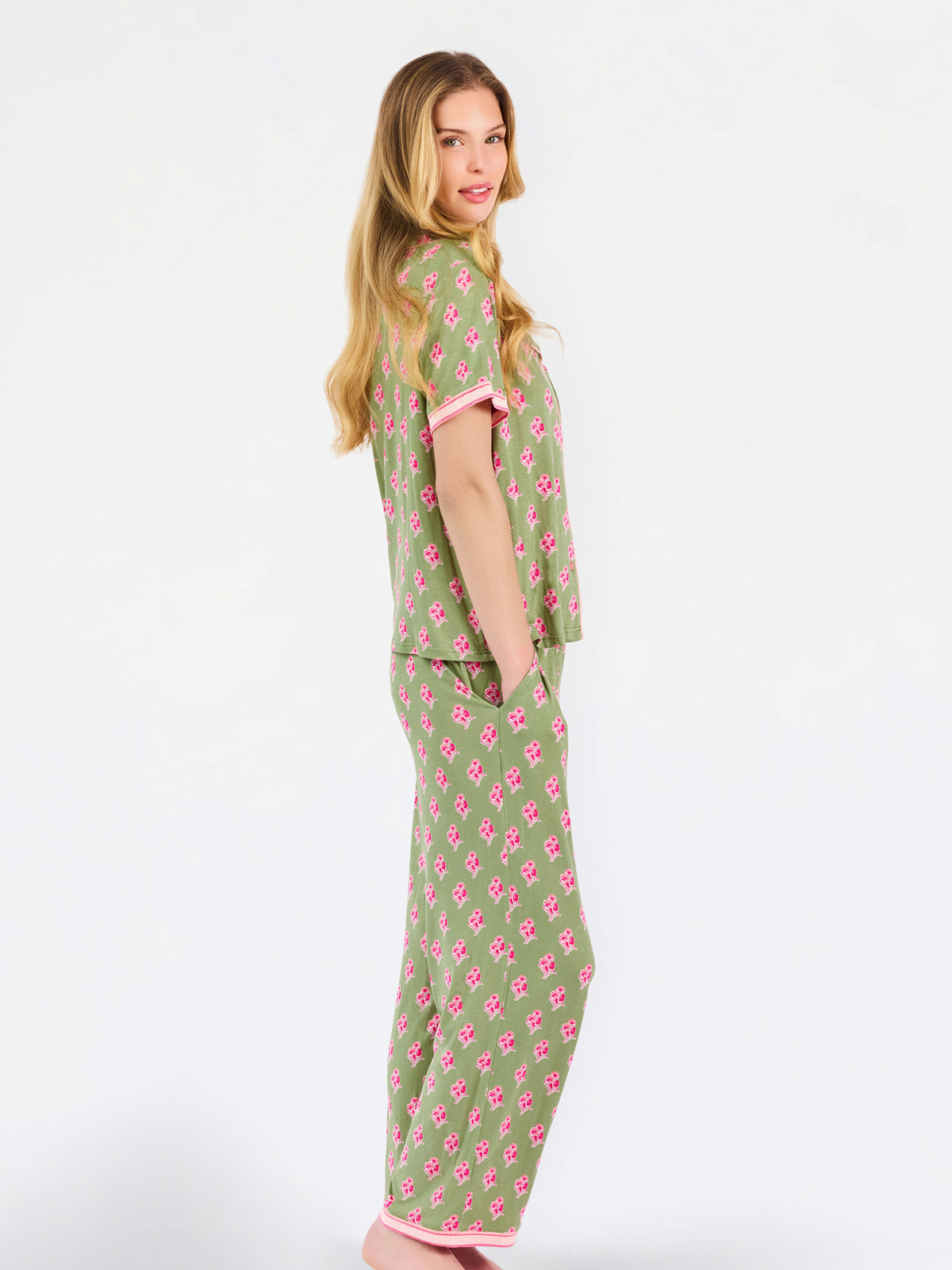 Woman wearing a green and pink floral pajama set on a white background