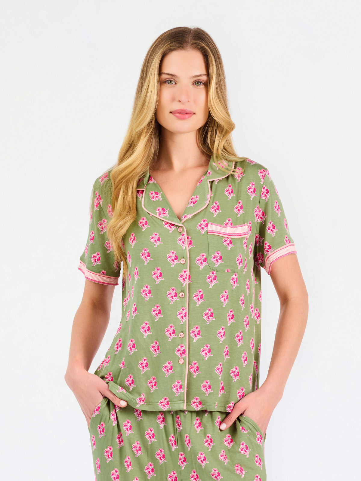 Woman wearing a green and pink floral pajama set on a white background