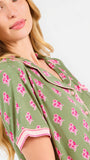 Woman wearing a green and pink floral pajama set on a white background