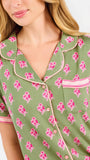Woman wearing a green and pink floral pajama set on a white background