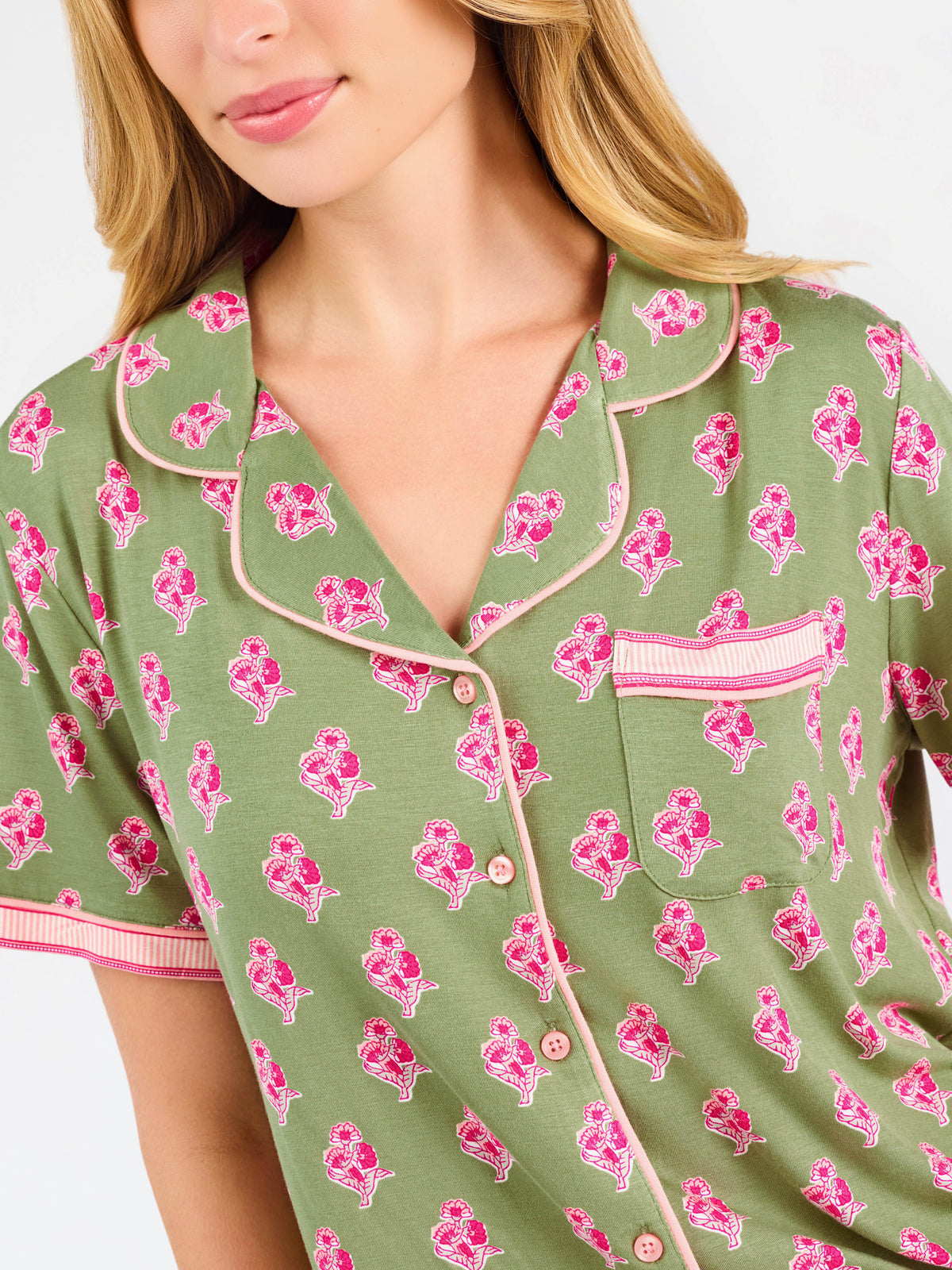 Woman wearing a green and pink floral pajama set on a white background