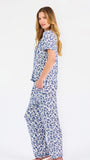 Blonde woman wearing a blue floral pajama set on a white background