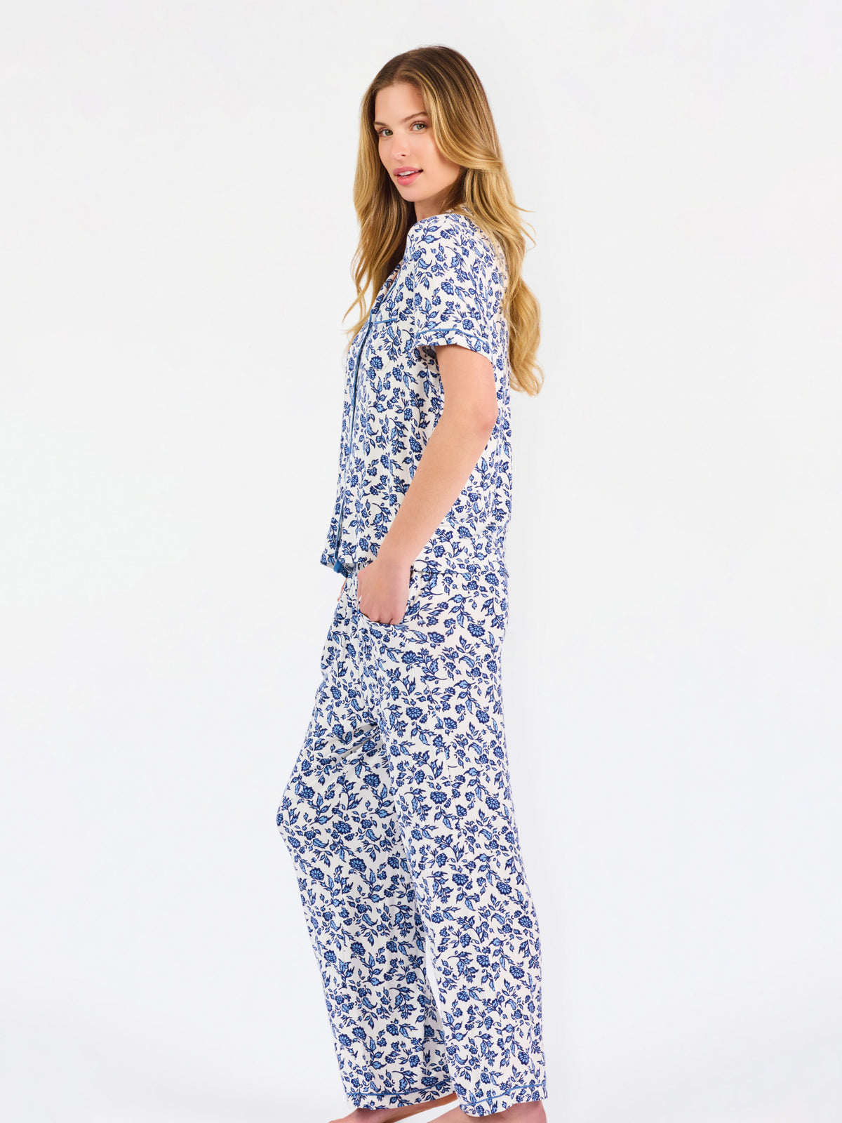 Blonde woman wearing a blue floral pajama set on a white background