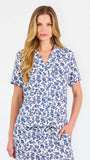 Blonde woman wearing a blue floral pajama set on a white background
