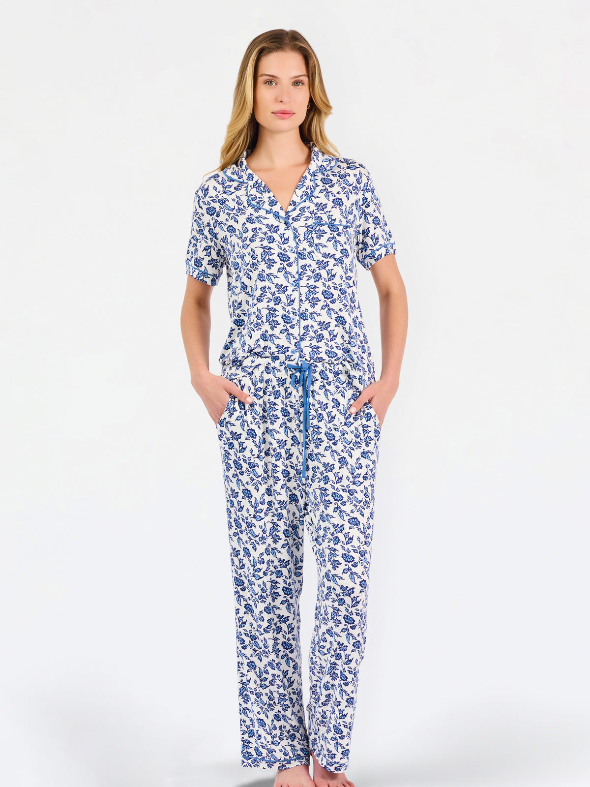 Blonde woman wearing a blue floral pajama set on a white background