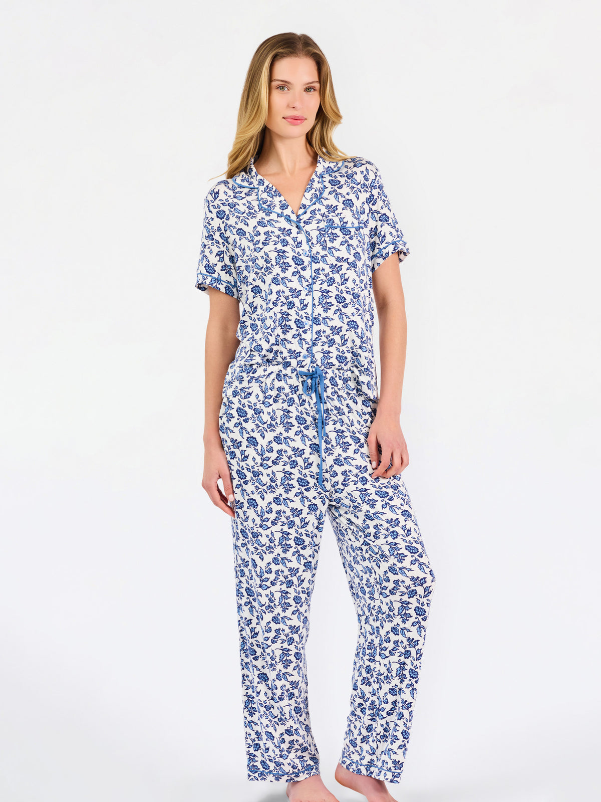 Blonde woman wearing a blue floral pajama set on a white background