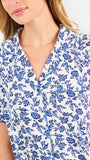 Blonde woman wearing a blue floral pajama set on a white background