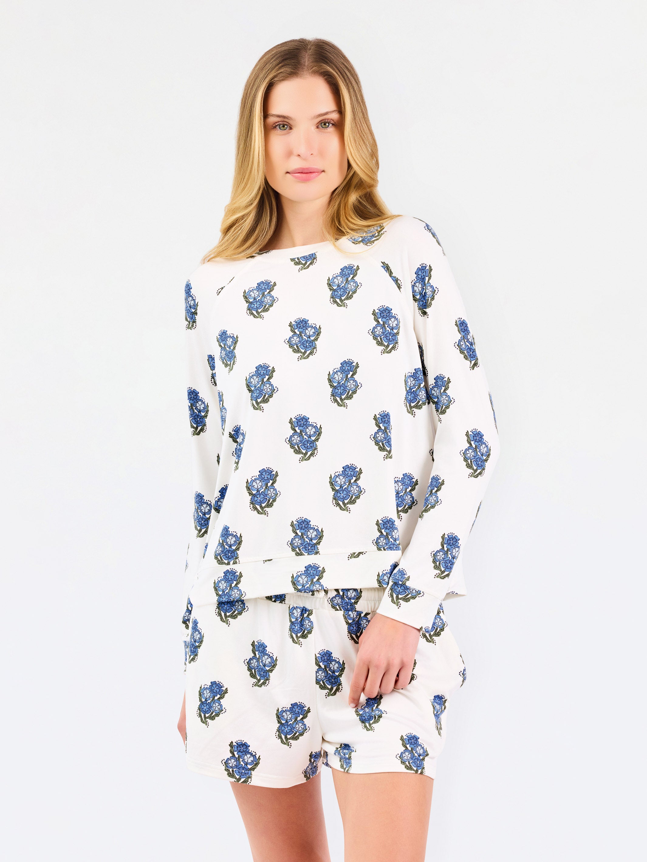 Woman wearing white pajamas with blue floral patterns on a white background