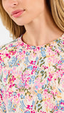 Blonde long haired woman wearing a multi colored floral long sleeve and shorts pajama set on a white background