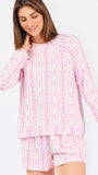 Short brown haired woman wearing a pink/purple floral pajama set on a white background