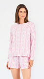 Short brown haired woman wearing a pink/purple floral pajama set on a white background