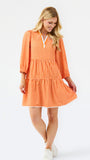 A woman modeling a tiered orange and white gingham mini dress with three-quarter sleeves and a split neckline, set against a plain white studio background.