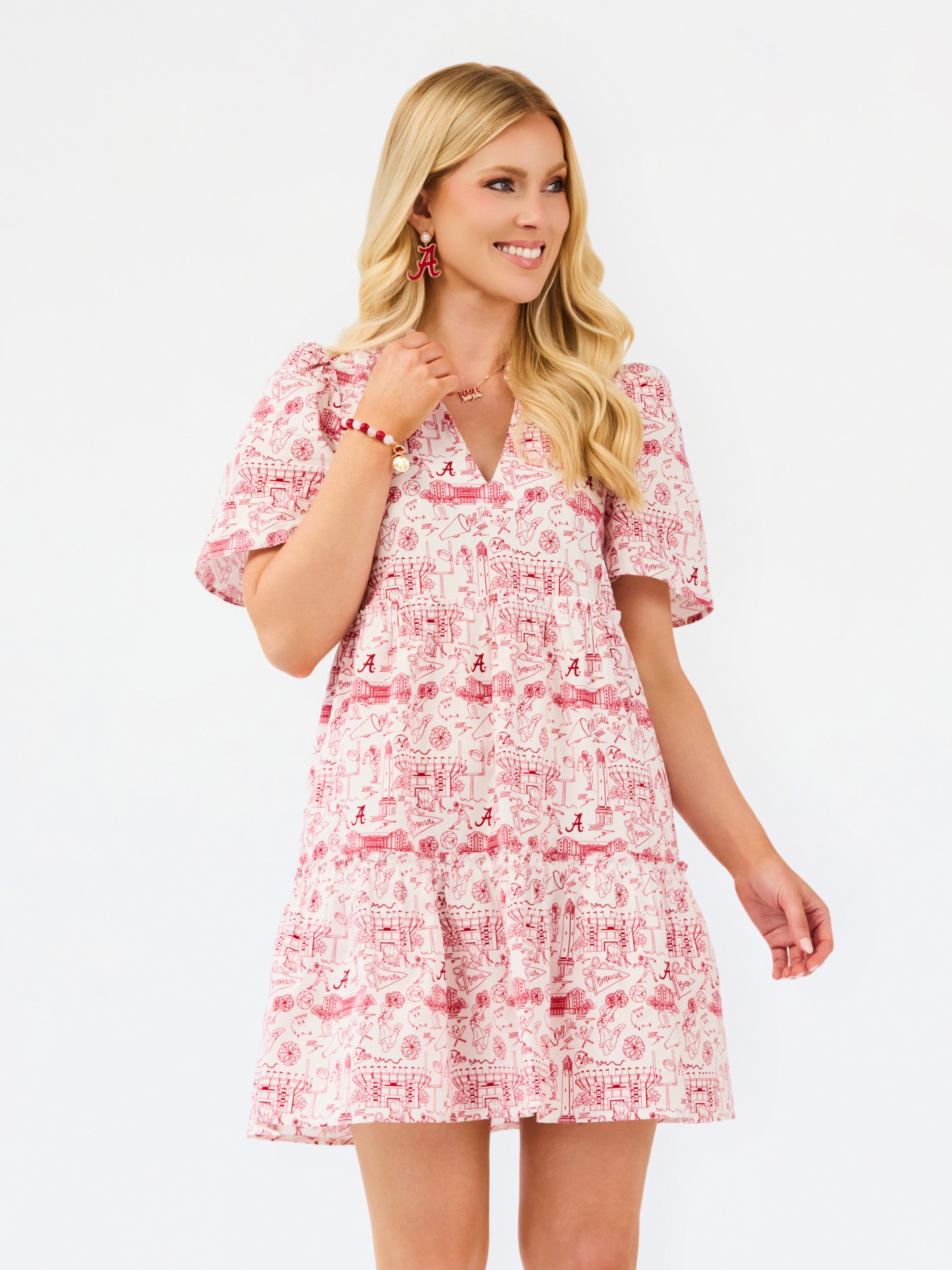 A woman modeling a short-sleeve tiered mini dress with a red and white toile-style print, set against a plain white studio background.